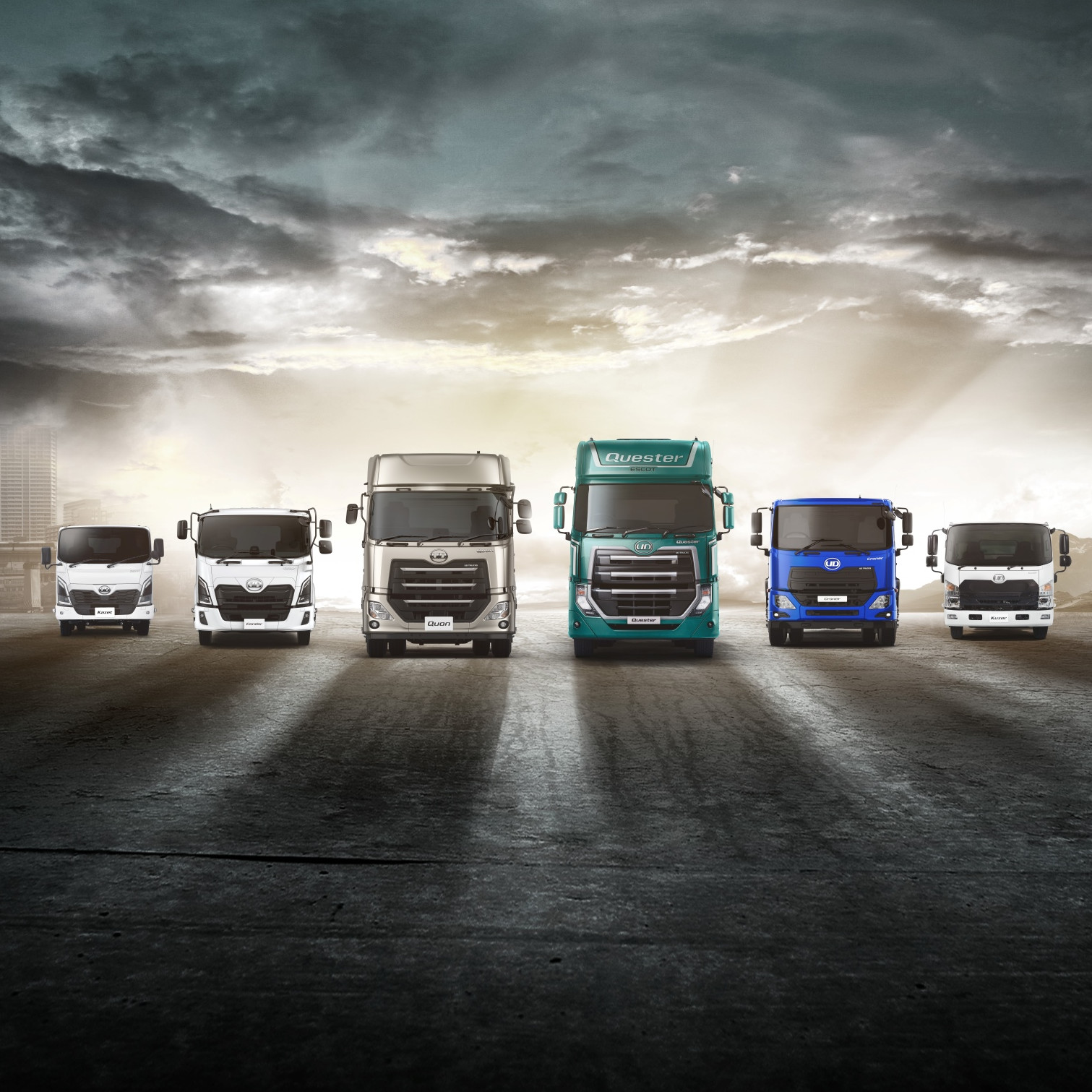 Six trucks of different sizes lined up on an open road under a dramatic sky.