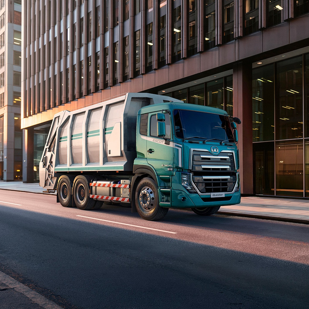 Garbage truck on an empty city street lined with tall modern buildings.