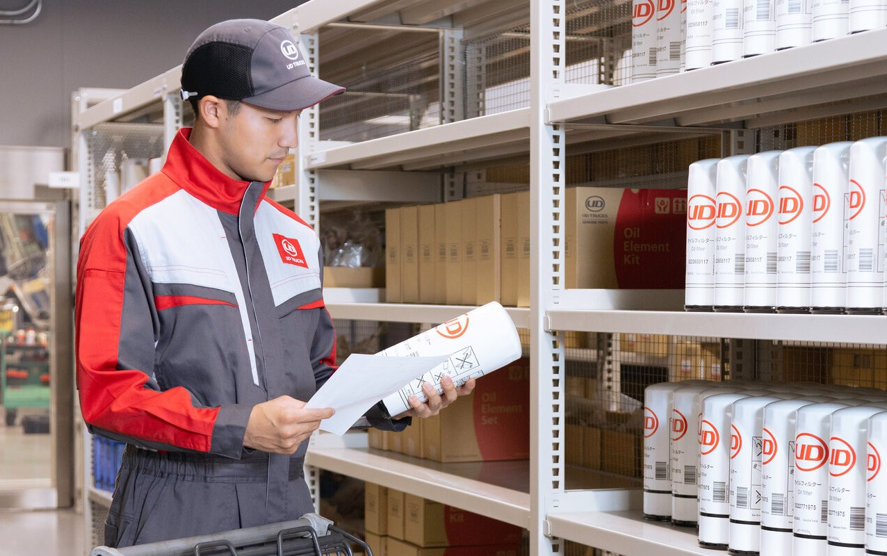 Worker in uniform checking inventory on shelves in a storeroom.