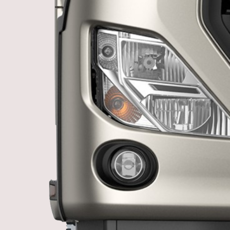 Close-up of a truck's headlight and fog light on a beige body.