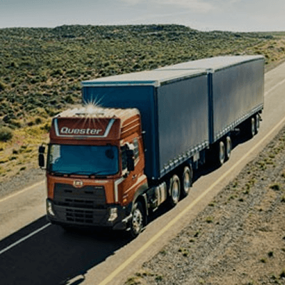 Xe tải container màu đỏ đang chạy trên đường vắng giữa vùng hoang mạc.