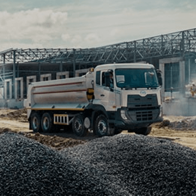 Dump truck sa construction site, may gusaling itinatayo sa likuran.