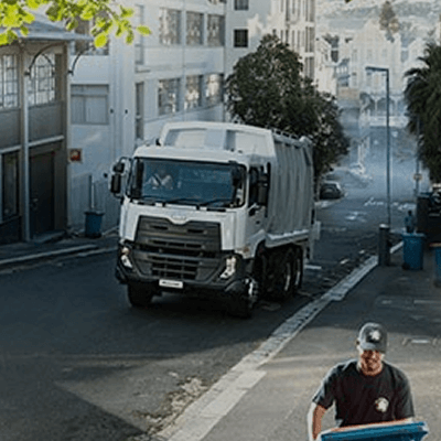 Xe tải rác màu trắng chạy trên phố, người công nhân đang thu gom rác.