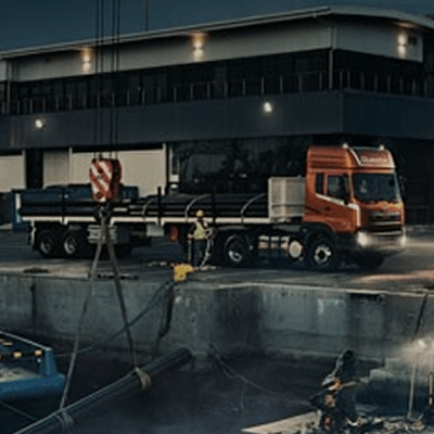 ညွန့်ပေါ်ရှိ အနီရောင်ထရပ်ကားနှင့် ဆောက်လုပ်ရေးလုပ်သည့်အလုပ်သမား