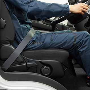青い作業服を着た人がシートベルトを締めて運転席に座っている