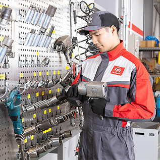作業着を着た整備士が工具を手に取り点検している