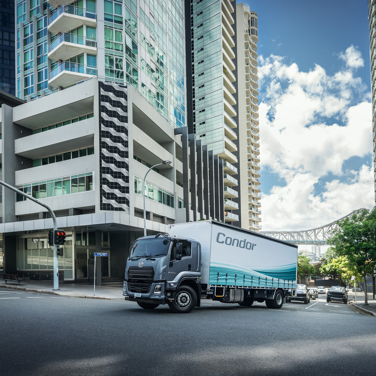 Large truck labeled "Candor" driving through modern city intersection.