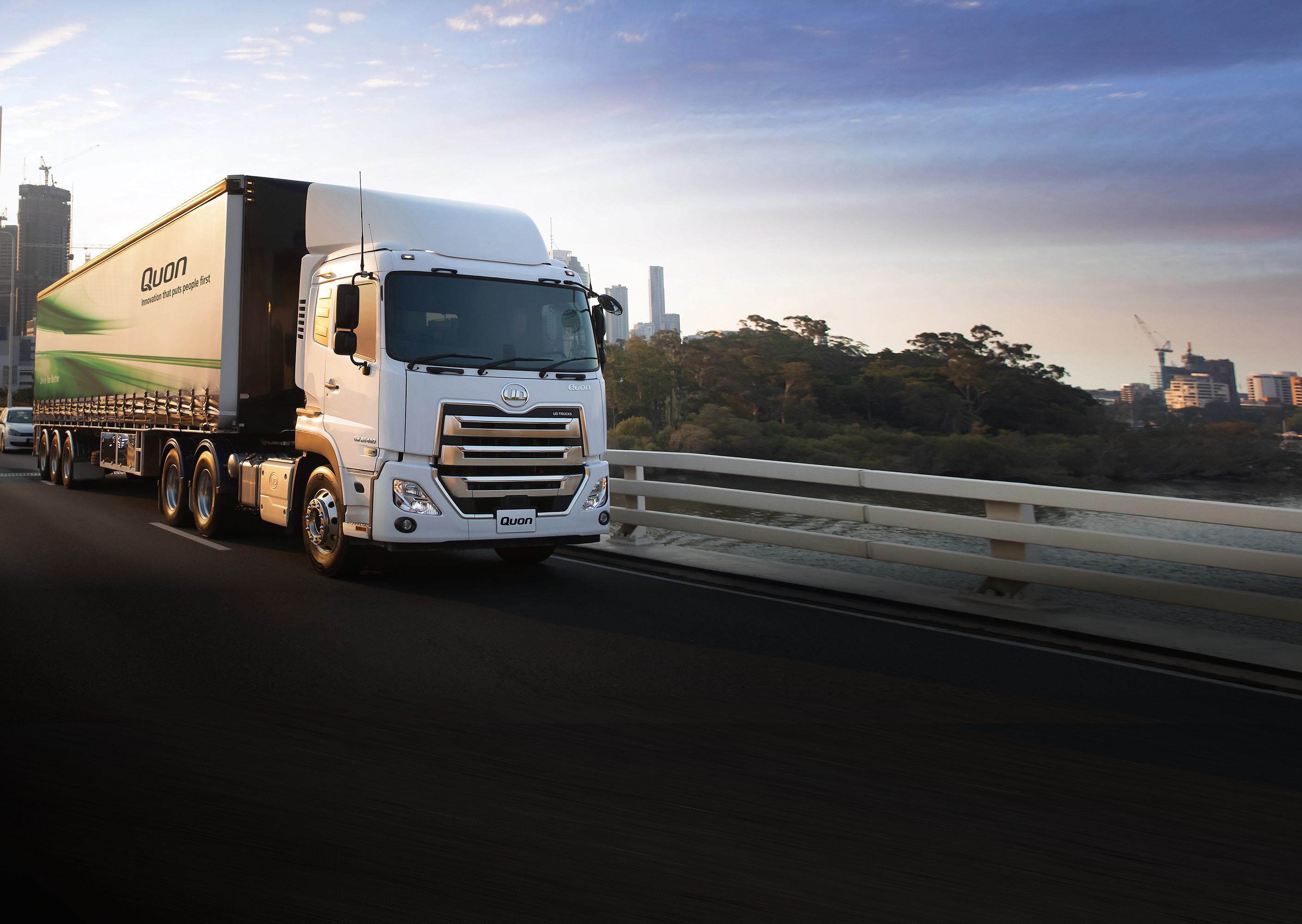 White semi-truck driving on a city bridge at sunrise