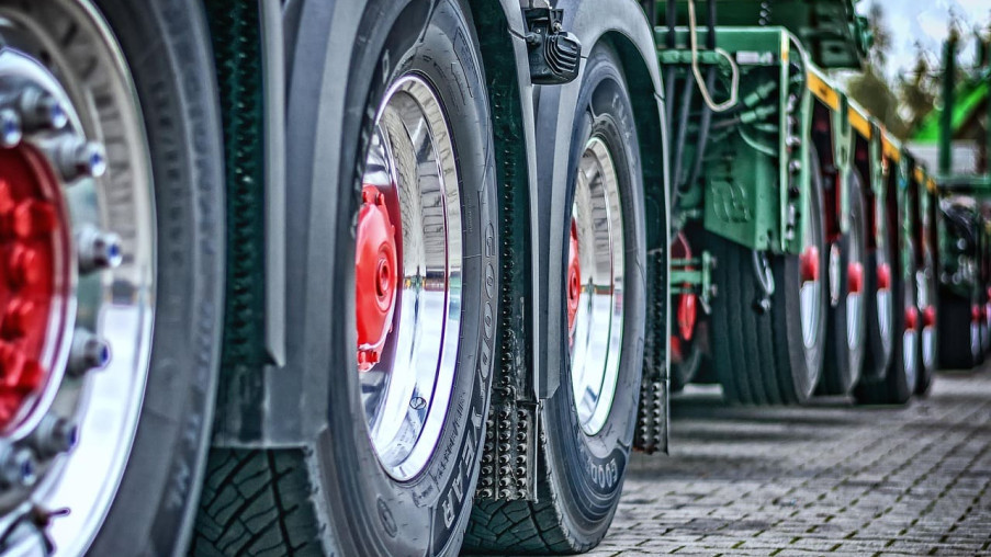 Close-up of large truck wheels lined up on a paved surface.