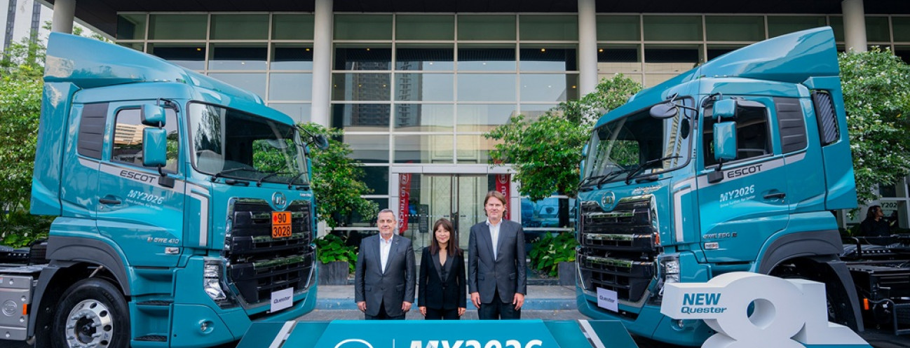 ผู้บริหารสามคนยืนหน้ารถบรรทุกสองคันสีฟ้า หน้าอาคารสำนักงาน