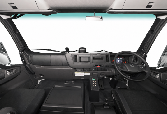Truck cab interior with steering wheel, dashboard, and two seats visible.